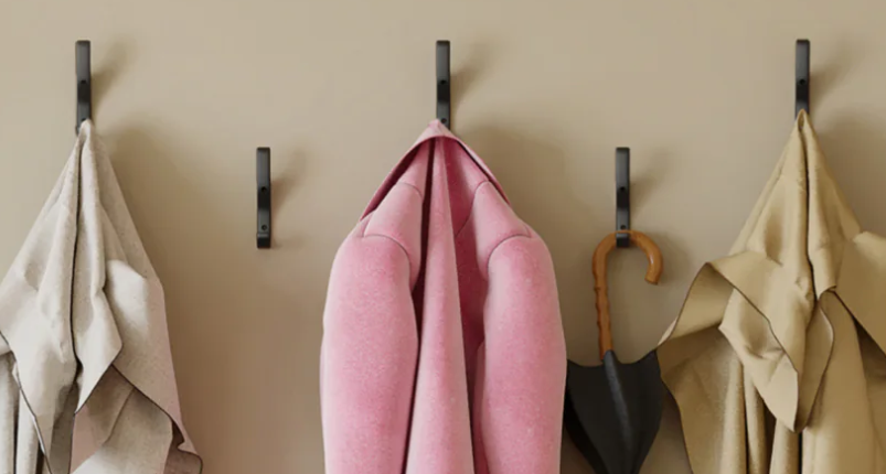 a row of black plastic hooks mounted on a brown wall, providing a sleek and functional organizational solution for hanging items in a public space.